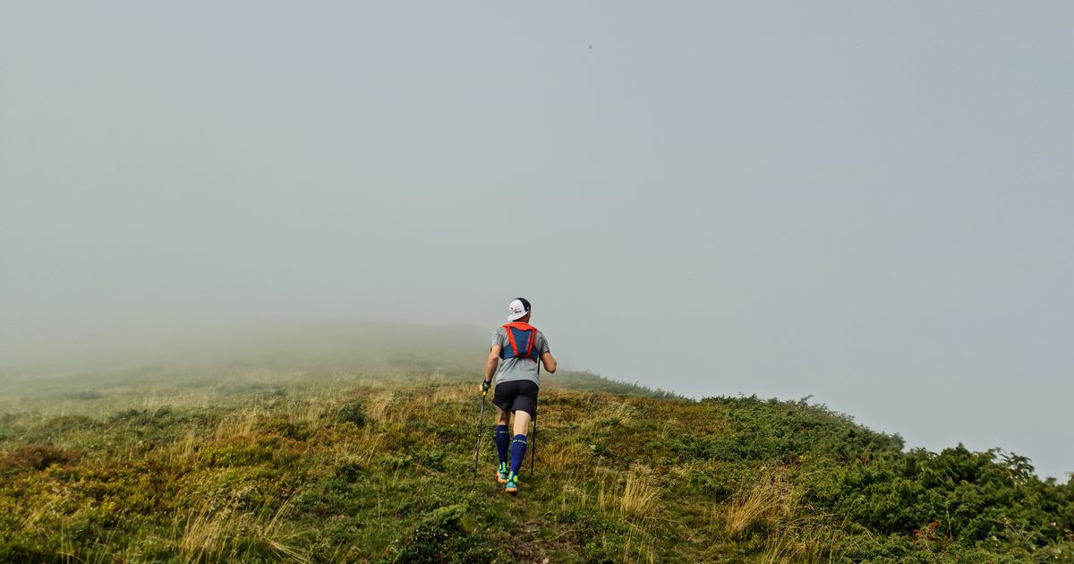 Coureur trail sur terrain gras et technique dans le brouillard