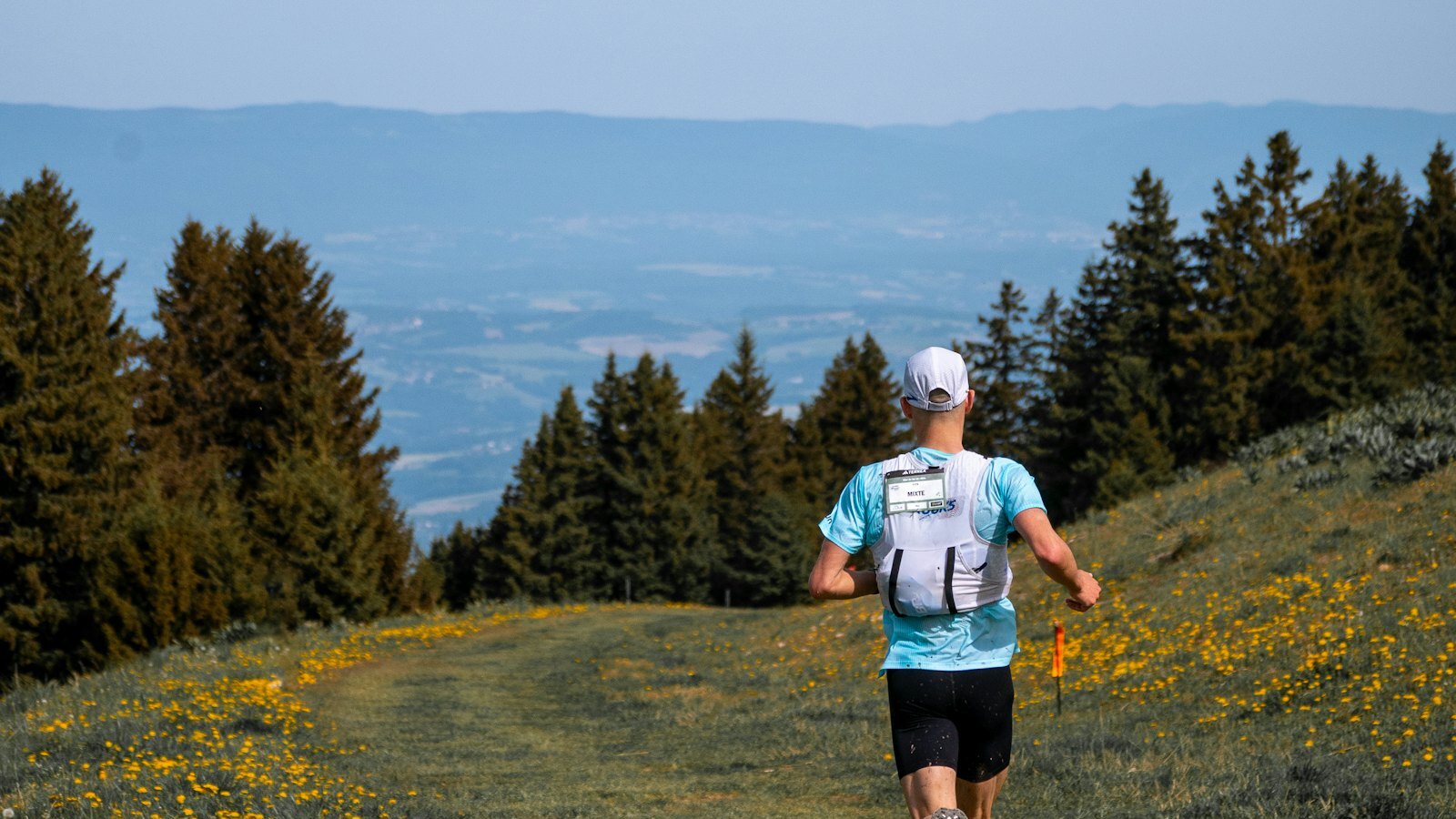 Traileur de dos avec gilet d'hydratation dans un paysage de montagne