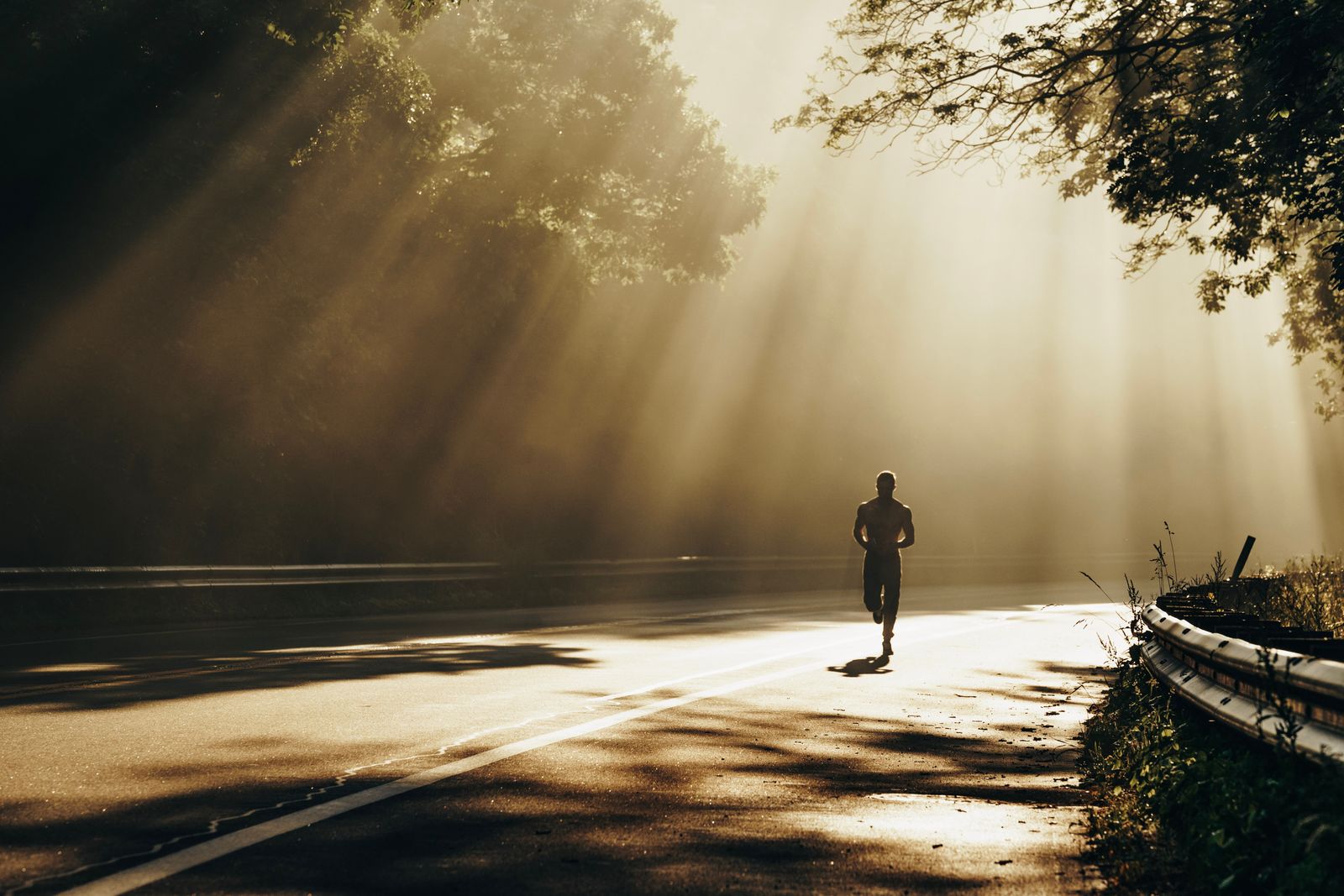 Coureur en silhouette courant sur une route au lever du soleil