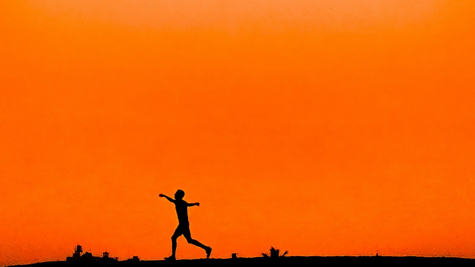 Silhouette d'un coureur sur fond de ciel orange